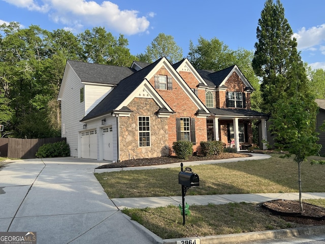 view of front facade with concrete driveway, a front lawn, stone siding, a shingled roof, and fence