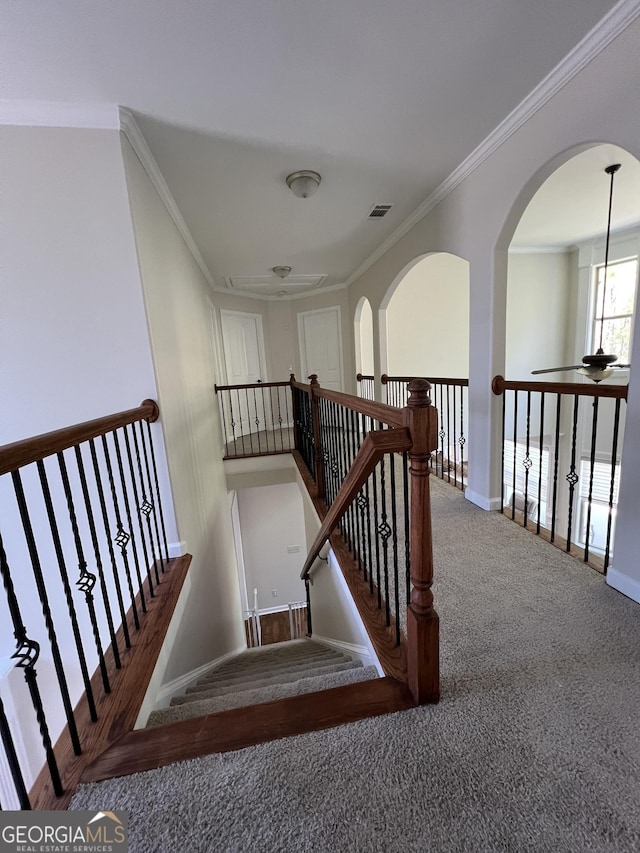staircase featuring arched walkways, baseboards, visible vents, carpet, and crown molding