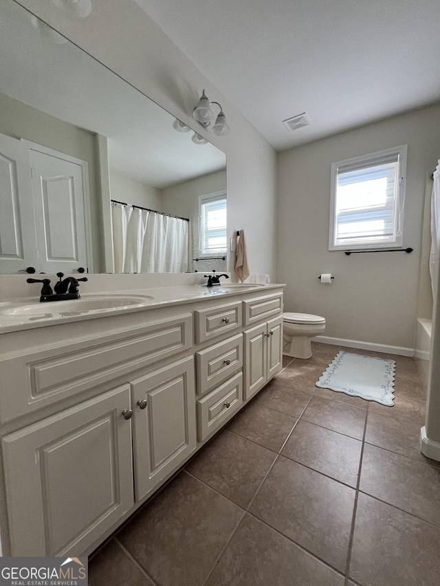 bathroom featuring tile patterned floors, a sink, double vanity, toilet, and visible vents