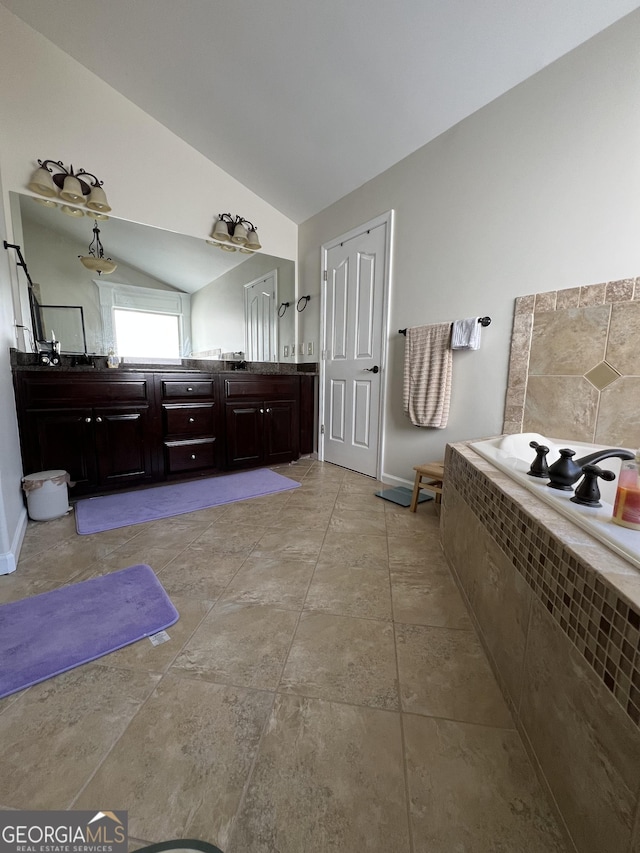 full bath featuring a bath, vaulted ceiling, double vanity, and baseboards