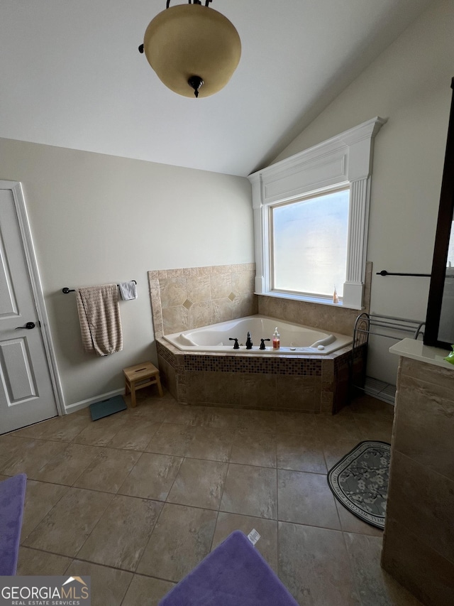 bathroom with a garden tub, vaulted ceiling, and tile patterned flooring