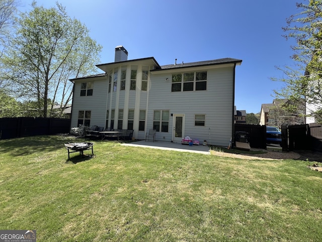 rear view of property featuring fence, a patio area, a chimney, and a yard