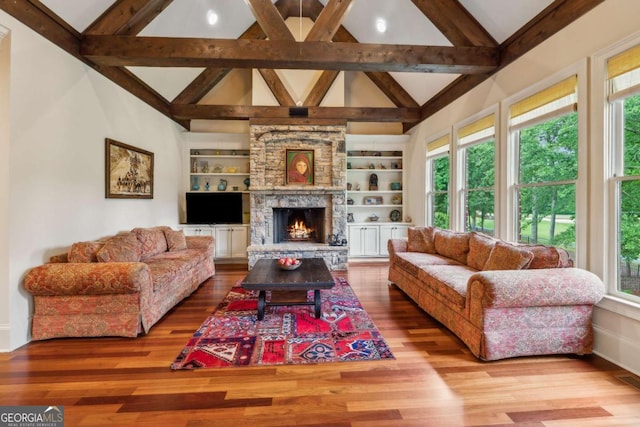 6935 Wakehurst Pl, Cumming, GA 30040 - living room featuring wood finished floors, a stone fireplace, baseboards, and built in shelves