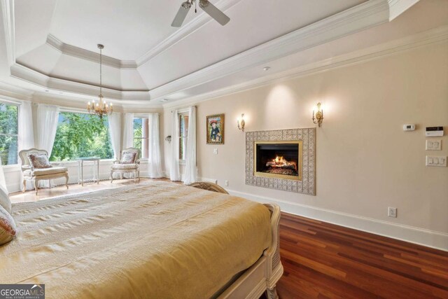 6935 Wakehurst Pl, Cumming, GA 30040 - bedroom featuring a fireplace, a tray ceiling, baseboards, wood finished floors, and crown molding