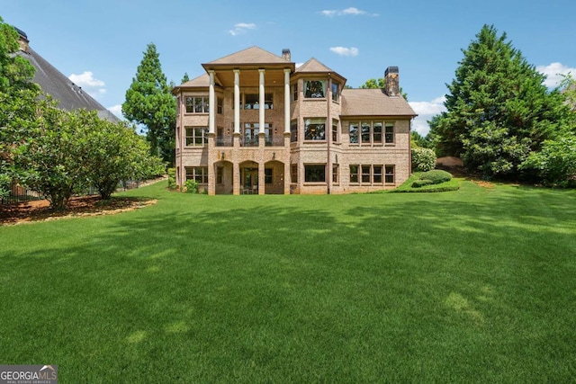 6935 Wakehurst Pl, Cumming, GA 30040 - rear view of house featuring a balcony, a chimney, a lawn, and brick siding