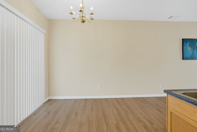 7112 Brookview Way, Riverdale, GA 30274 - unfurnished dining area with a notable chandelier, baseboards, a sink, and light wood-style flooring