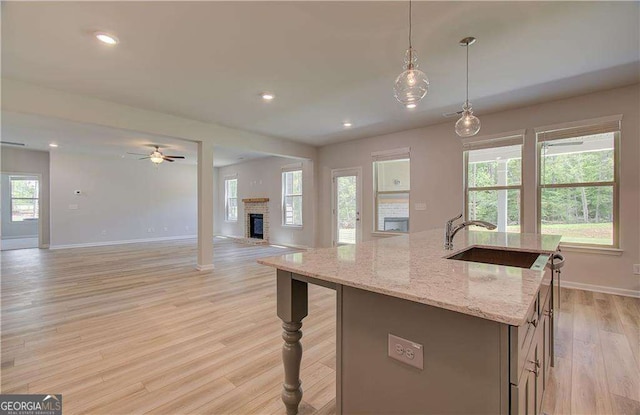140 Cooper Cv E Lot 21, Fayetteville, GA 30215 - kitchen with light wood-type flooring, a ceiling fan, open floor plan, a fireplace, and a kitchen island with sink