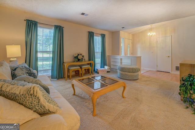living area with a chandelier, a textured ceiling, wood finished floors, and visible vents