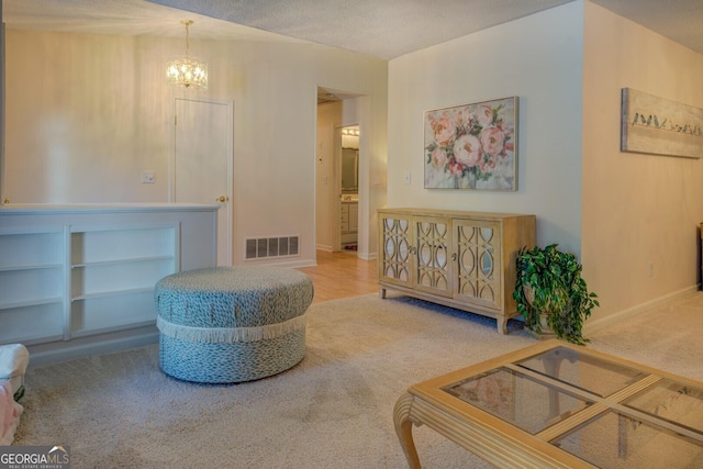living area featuring carpet flooring, visible vents, baseboards, and an inviting chandelier