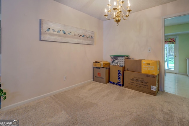 carpeted spare room featuring baseboards and a notable chandelier