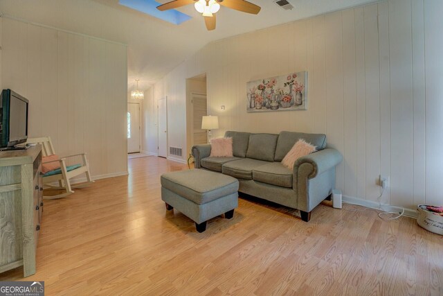 living room featuring visible vents, light wood-type flooring, ceiling fan with notable chandelier, and lofted ceiling