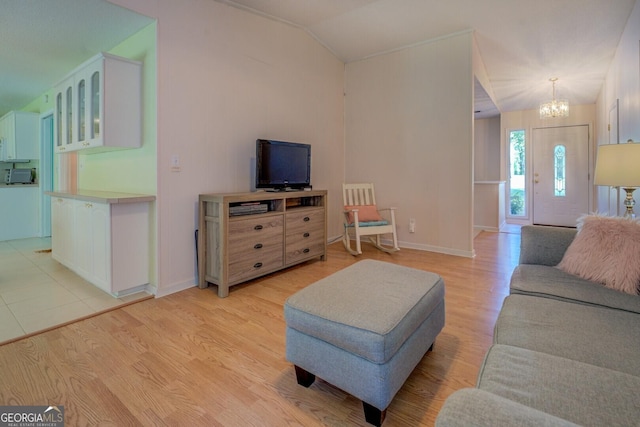 living area with light wood finished floors, an inviting chandelier, baseboards, and vaulted ceiling
