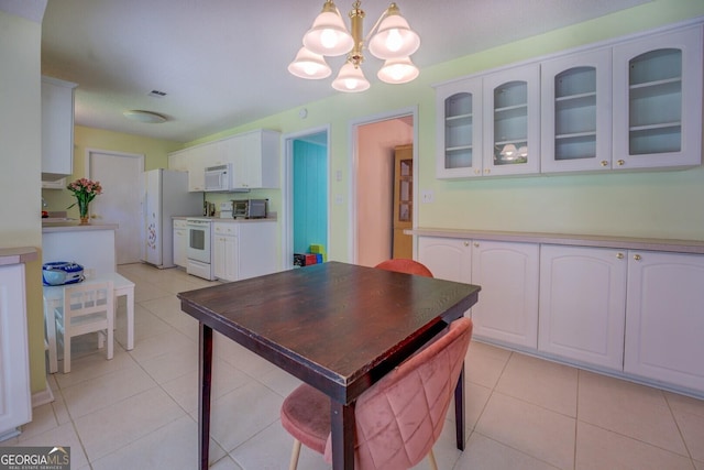 kitchen with an inviting chandelier, light tile patterned floors, glass insert cabinets, white appliances, and white cabinets