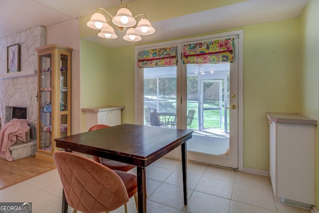 dining area with a chandelier, light tile patterned floors, baseboards, and a stone fireplace