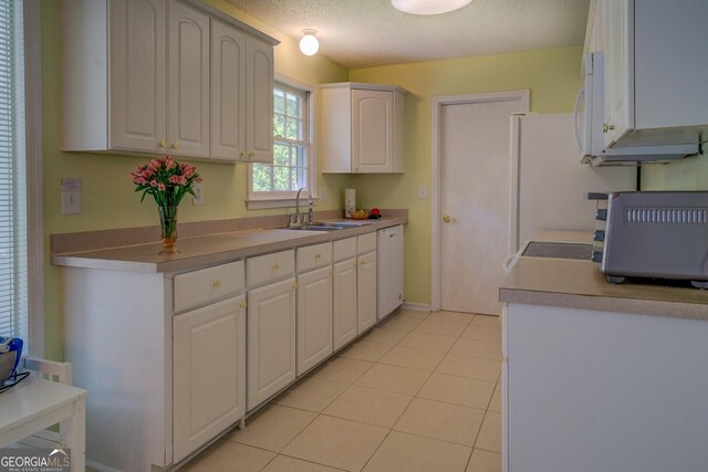 kitchen with light tile patterned floors, white appliances, a textured ceiling, white cabinetry, and a sink