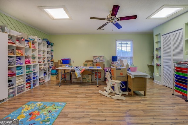 recreation room with ornamental molding, ceiling fan, and wood finished floors