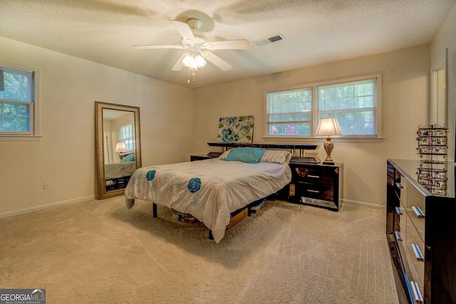 bedroom featuring ceiling fan, carpet, a textured ceiling, visible vents, and baseboards