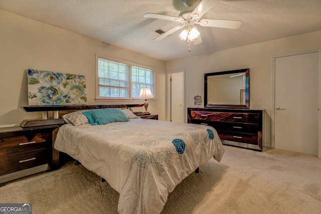 carpeted bedroom featuring a textured ceiling, a ceiling fan, and visible vents