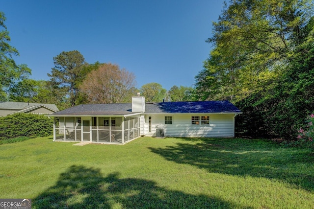 rear view of property with a lawn, a sunroom, and a chimney