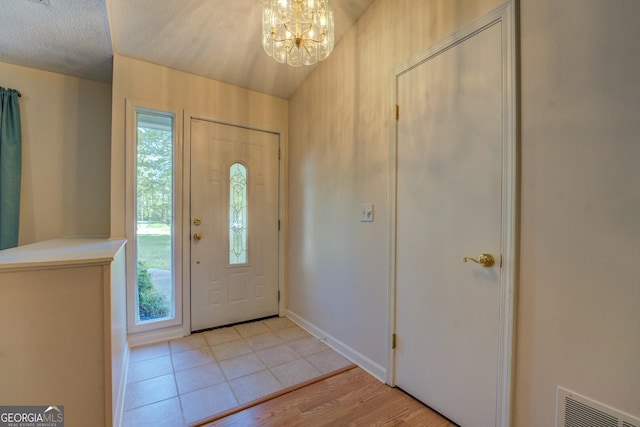 foyer with visible vents, plenty of natural light, a chandelier, and a textured ceiling