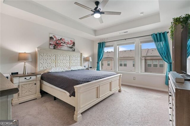 bedroom featuring light carpet, visible vents, baseboards, and a raised ceiling