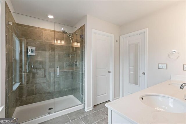 full bathroom with a sink, tile patterned floors, a shower stall, and double vanity