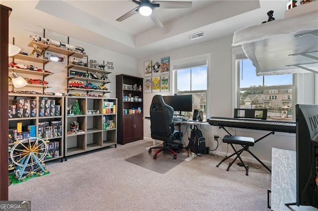 home office with a raised ceiling, visible vents, ceiling fan, and carpet floors