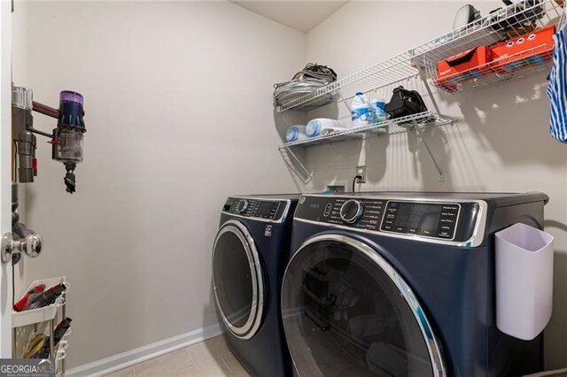 laundry area with washer and clothes dryer, light tile patterned floors, laundry area, and baseboards