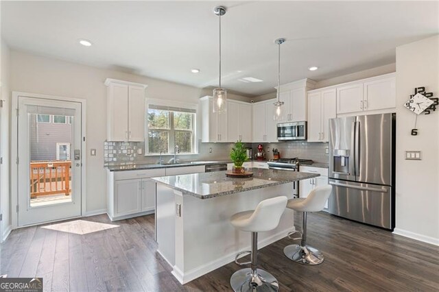 kitchen with tasteful backsplash, white cabinets, a sink, appliances with stainless steel finishes, and dark wood-style floors