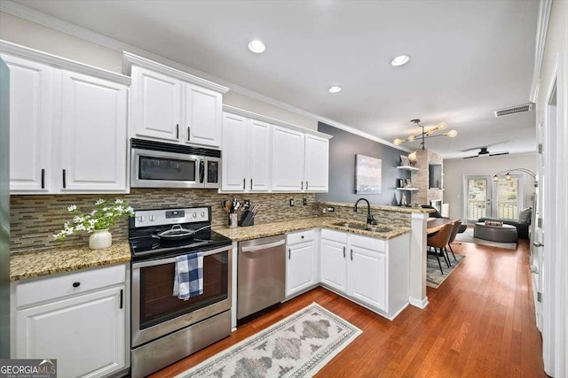 kitchen featuring a sink, white cabinets, a peninsula, and stainless steel appliances