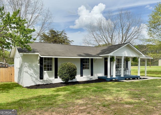 ranch-style home featuring a porch, fence, a shingled roof, and a front lawn