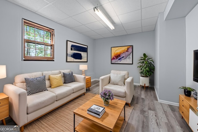 living room featuring baseboards, a paneled ceiling, and wood finished floors