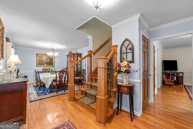 staircase featuring wood-type flooring, a chandelier, and crown molding
