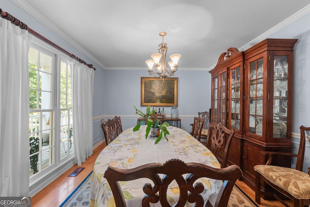 dining space featuring a chandelier, ornamental molding, and light wood-type flooring