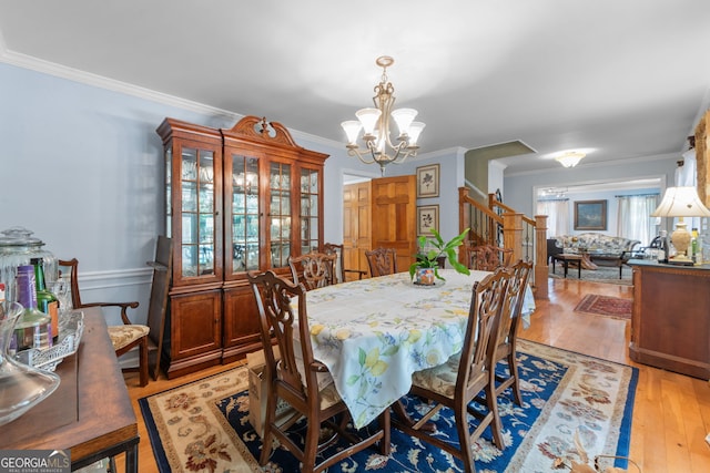 dining room with stairway, a chandelier, crown molding, and light wood-style floors