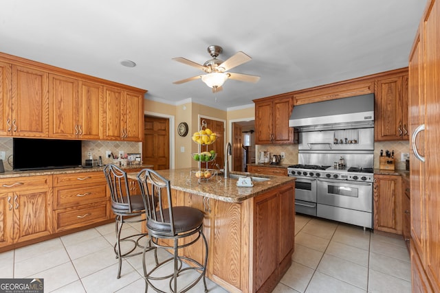 kitchen featuring wall chimney range hood, a sink, double oven range, decorative backsplash, and ornamental molding