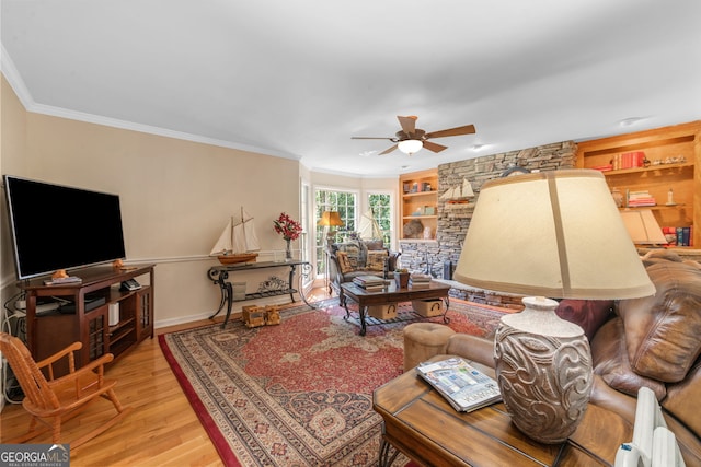 living area with a ceiling fan, ornamental molding, wood finished floors, baseboards, and built in features