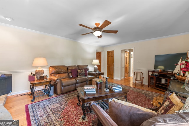 living area with a ceiling fan, wood finished floors, ornamental molding, and baseboards