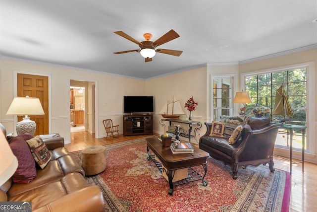 living area featuring wood finished floors, ceiling fan, and ornamental molding