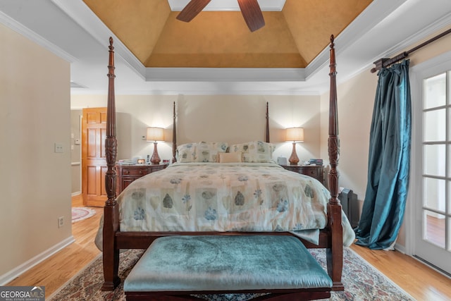 bedroom with wood finished floors, ornamental molding, baseboards, lofted ceiling, and a ceiling fan