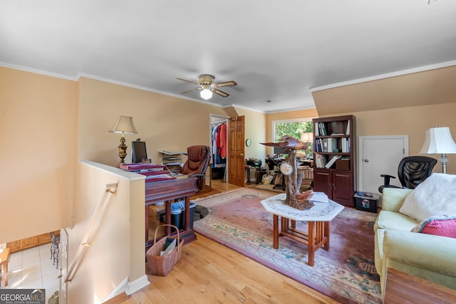 living area with crown molding, a ceiling fan, wood finished floors, and baseboards