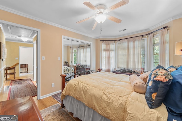 bedroom with attic access, wood finished floors, a closet, crown molding, and baseboards