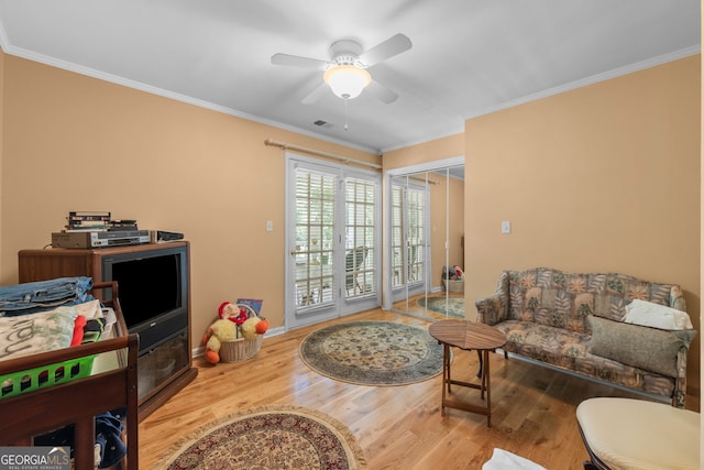 living room with wood finished floors, crown molding, ceiling fan, and baseboards