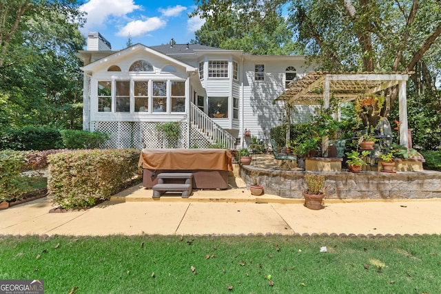 back of house with a chimney, a patio, a hot tub, and a sunroom