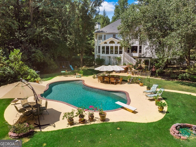 outdoor pool featuring a patio, a lawn, a diving board, stairway, and a sunroom