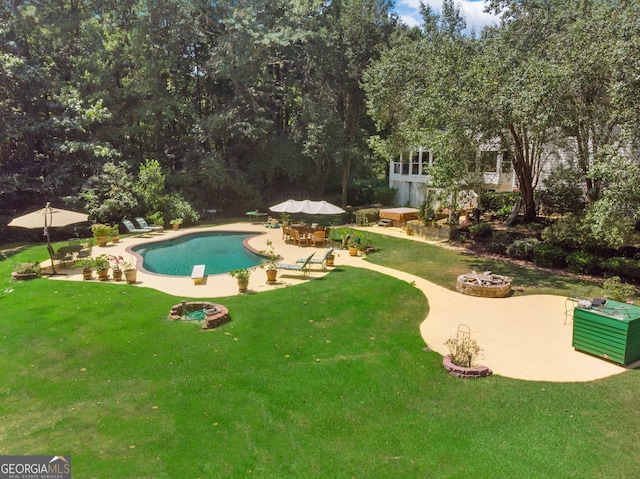 outdoor pool with a fire pit, a patio area, and a yard