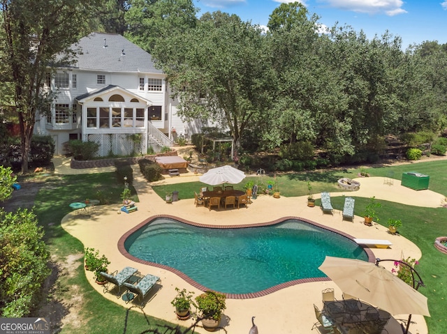 outdoor pool with a patio area, a lawn, a diving board, and outdoor dining area