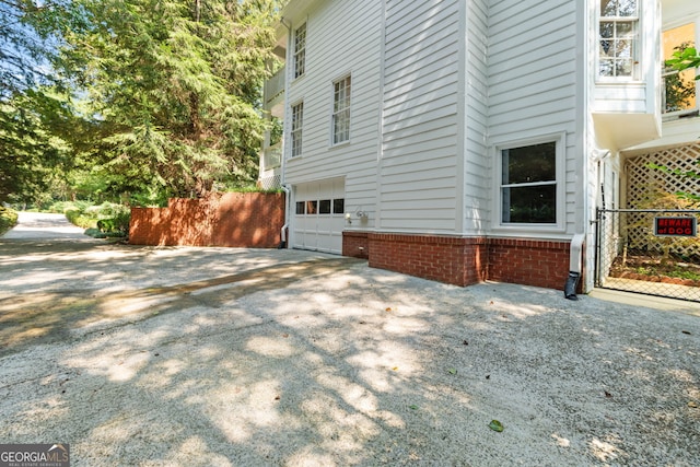view of home's exterior featuring an attached garage, fence, and driveway