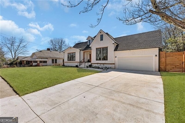 view of front of house featuring driveway, an attached garage, a front yard, brick siding, and fence