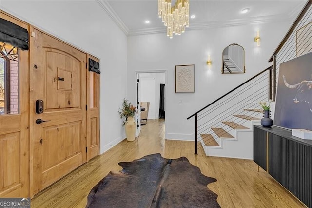 entryway featuring baseboards, a chandelier, crown molding, stairs, and light wood-style floors